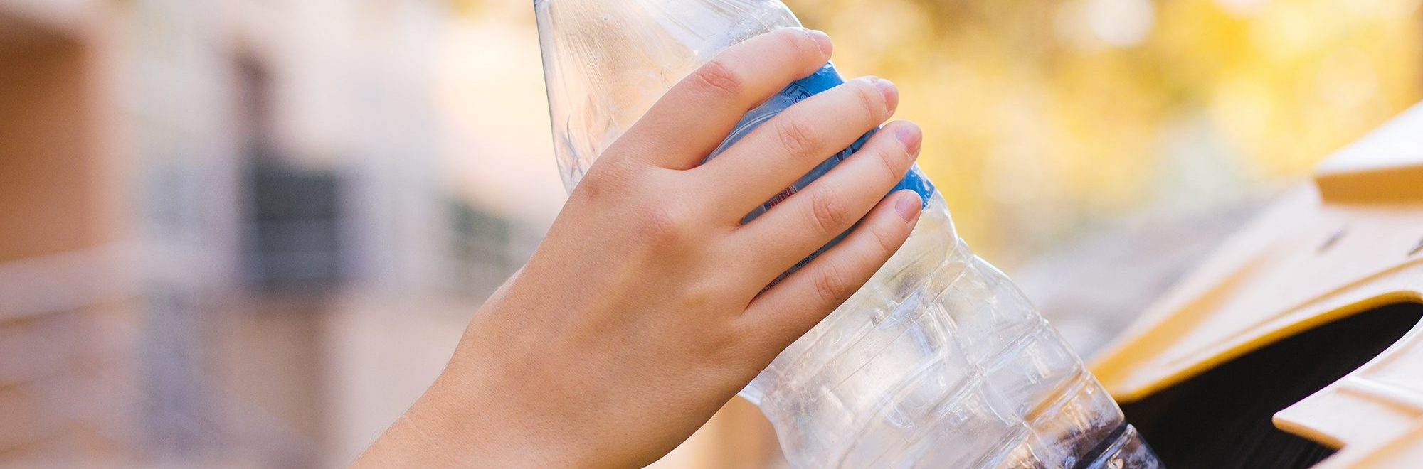 photo of a woman's hand recycling a plastic bottle